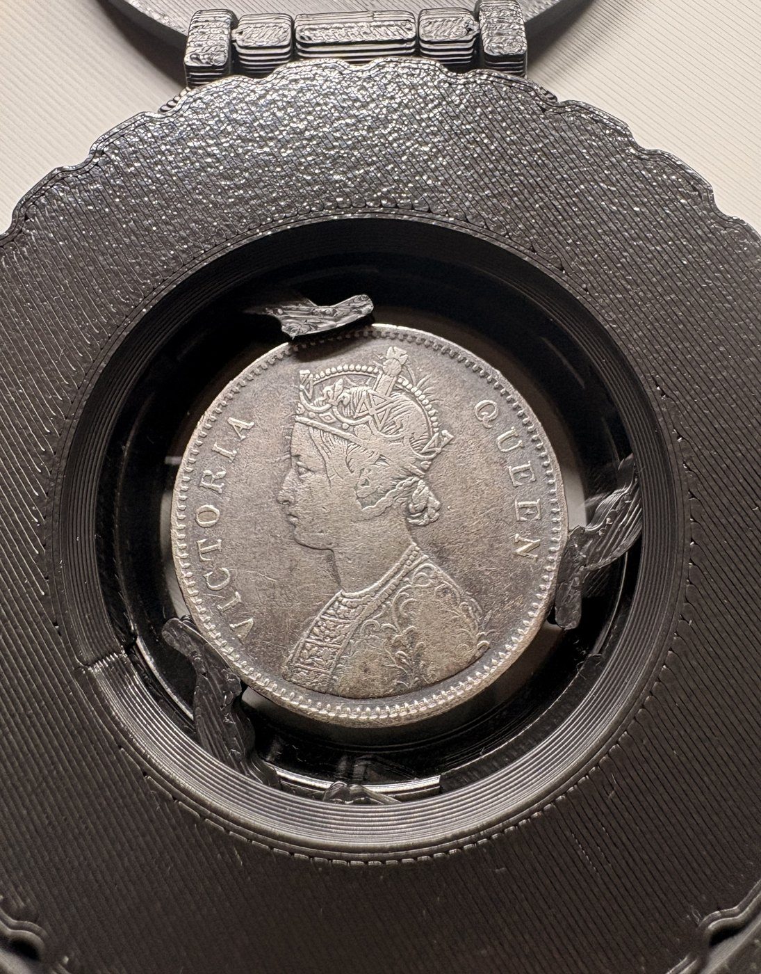An 1862 Victoria rupee held by three talons inside the Talon Capsule, lid open